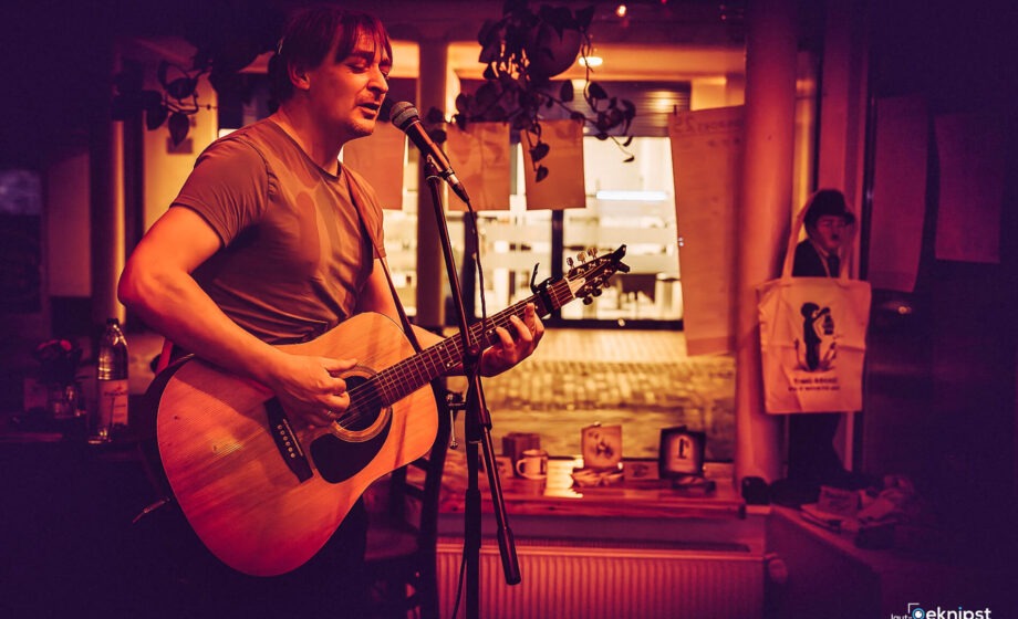 Musiker spielt Gitarre und singt im Café.