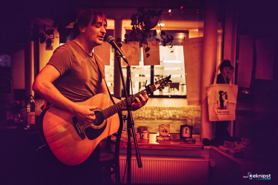 Musiker spielt Gitarre und singt im Café.