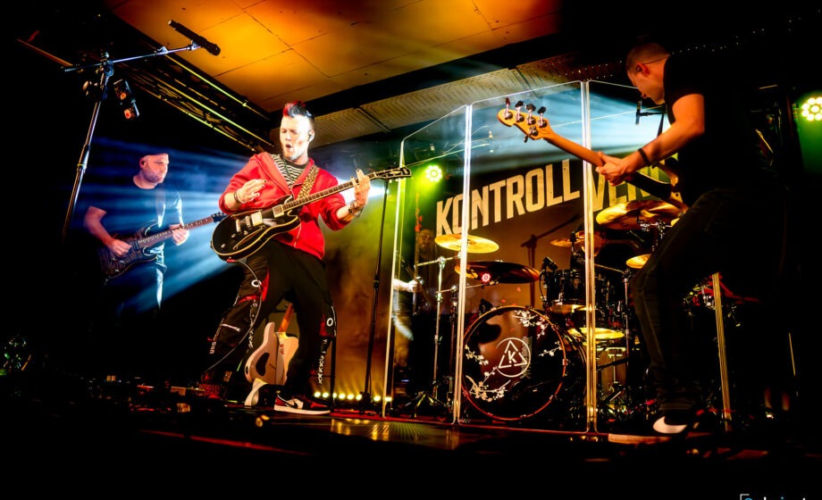 Band spielt live auf Bühne mit Lichteffekten.
