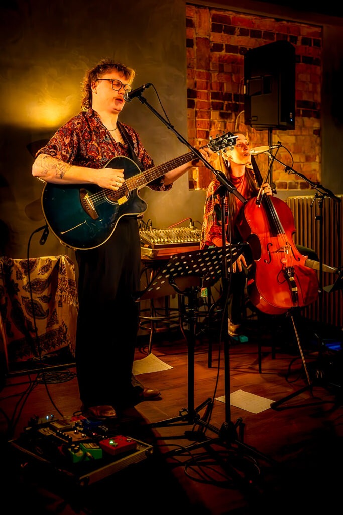 Zwei Musiker spielen Gitarre und Cello auf der Bühne.