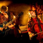 Zwei Musiker spielen Gitarre und Cello auf der Bühne.