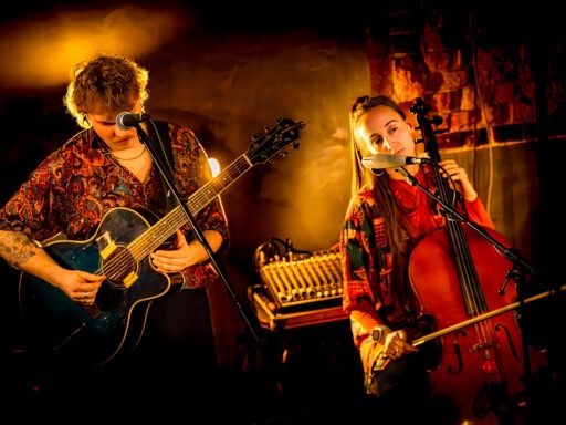 Zwei Musiker spielen Gitarre und Cello auf der Bühne.