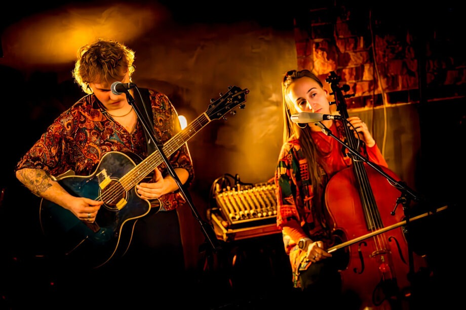 Zwei Musiker spielen Gitarre und Cello auf der Bühne.