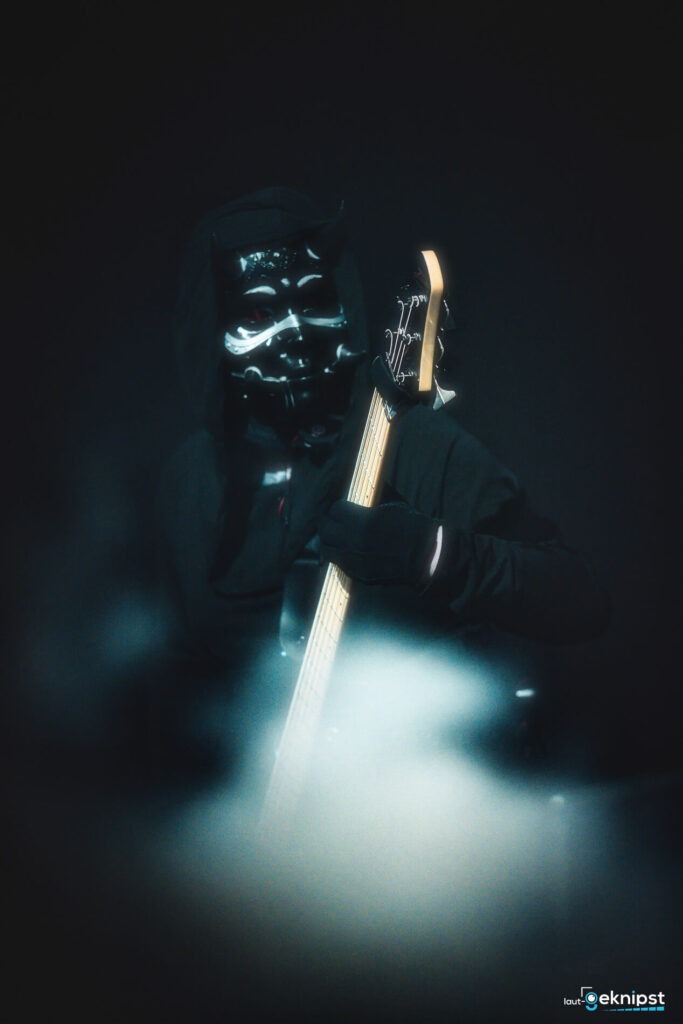 Musiker in Maske spielt E-Gitarre im Nebel.