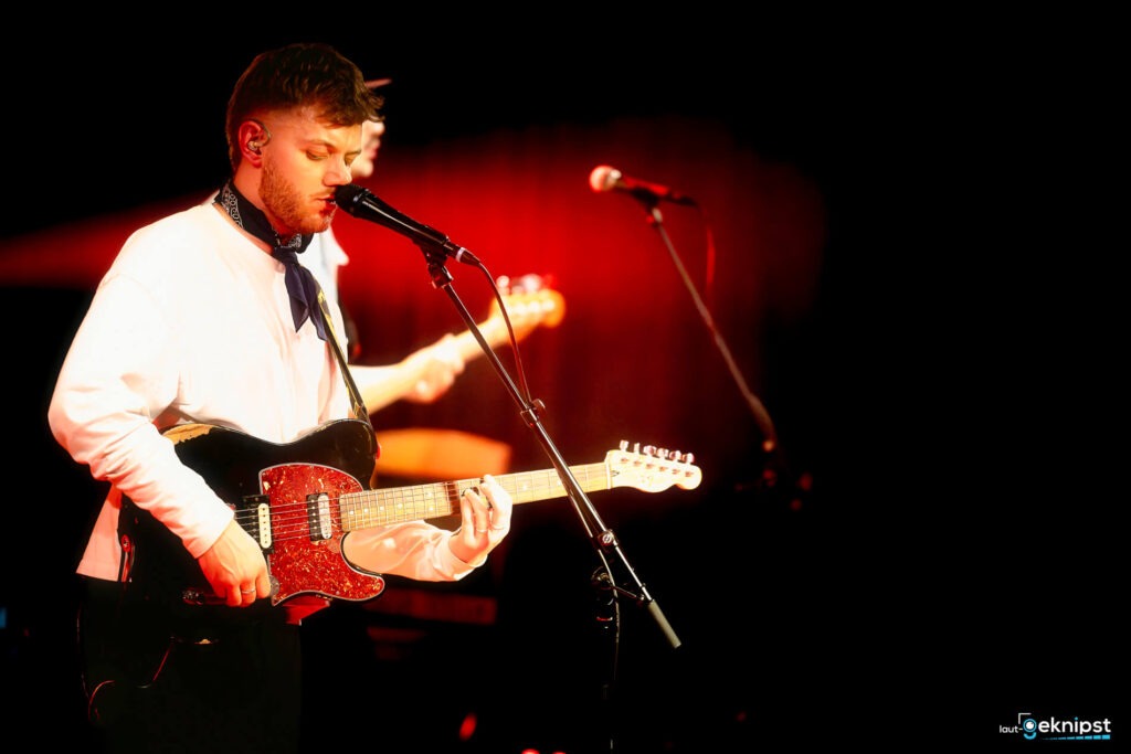 Mann singt und spielt Gitarre auf Bühne