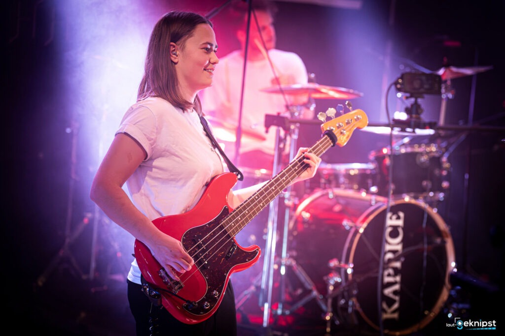 Bassistin spielt auf roter Gitarre, live auf Bühne.