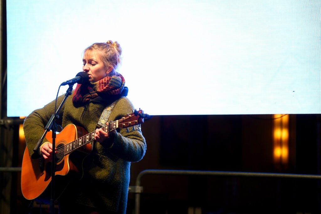 Frau singt und spielt Gitarre auf Bühne