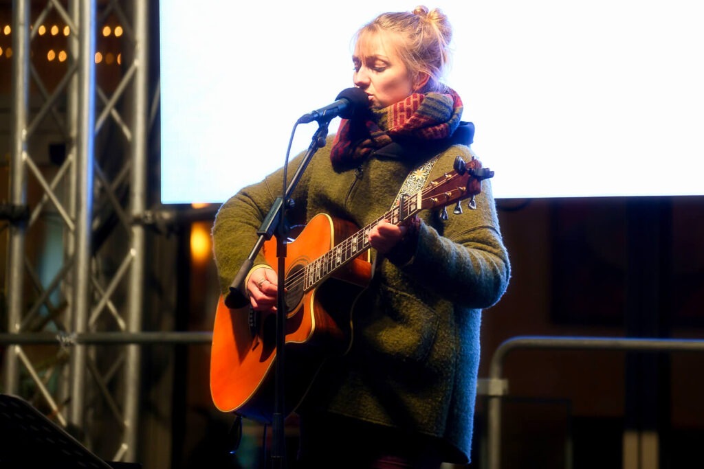 Frau spielt Gitarre auf der Bühne.