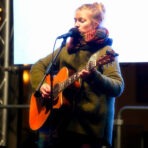 Frau spielt Gitarre auf der Bühne.