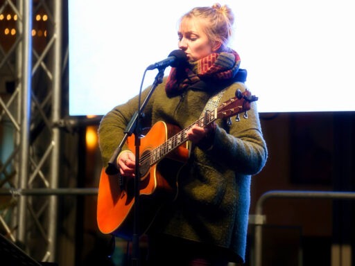 Frau spielt Gitarre auf der Bühne.