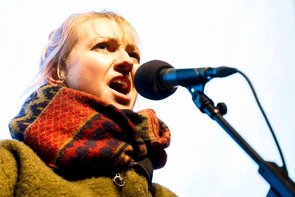 Person singt in Mikrofon mit buntem Schal