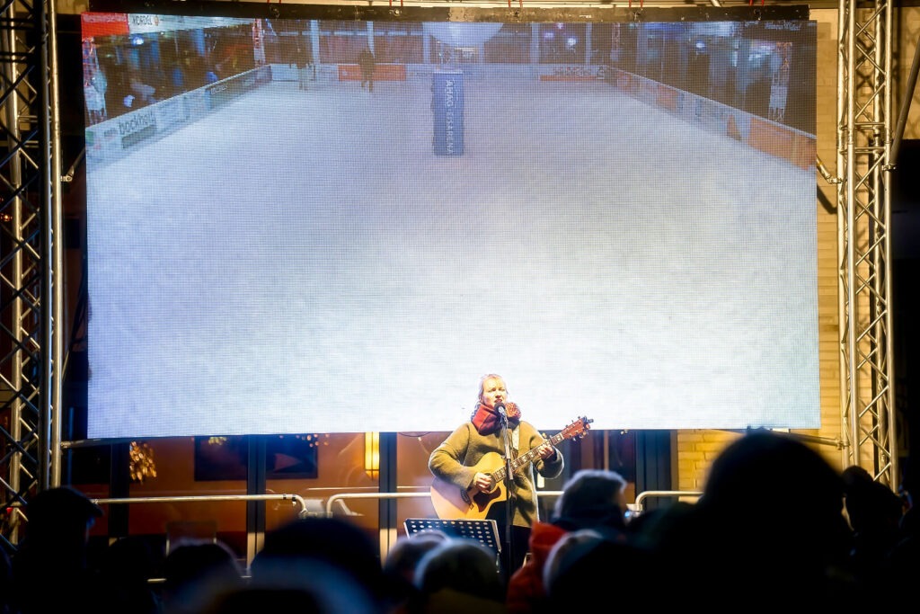 Musiker spielt Gitarre unter großer Leinwand