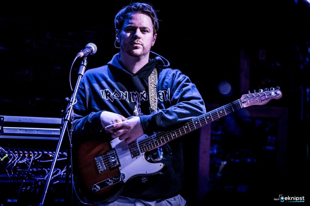 Musiker mit Gitarre und Mikrofon auf der Bühne