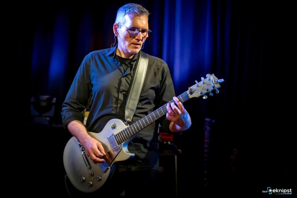 Gitarrist spielt auf der Bühne mit E-Gitarre.