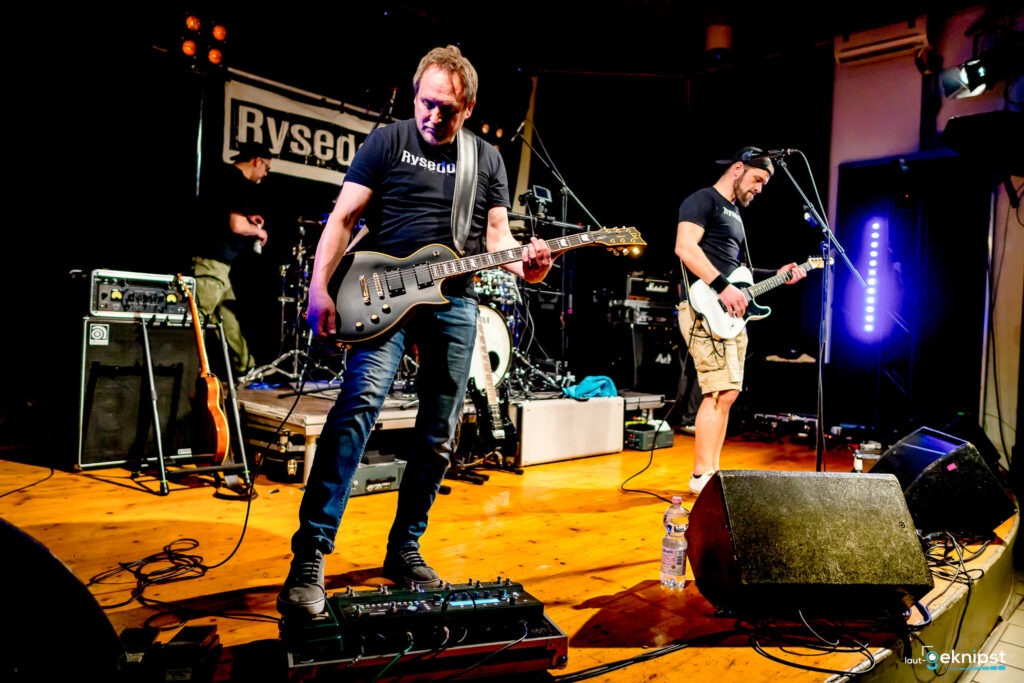 Zwei Musiker spielen auf der Bühne mit Gitarren.