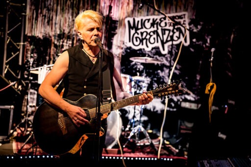 Musiker spielt Gitarre auf Bühne.