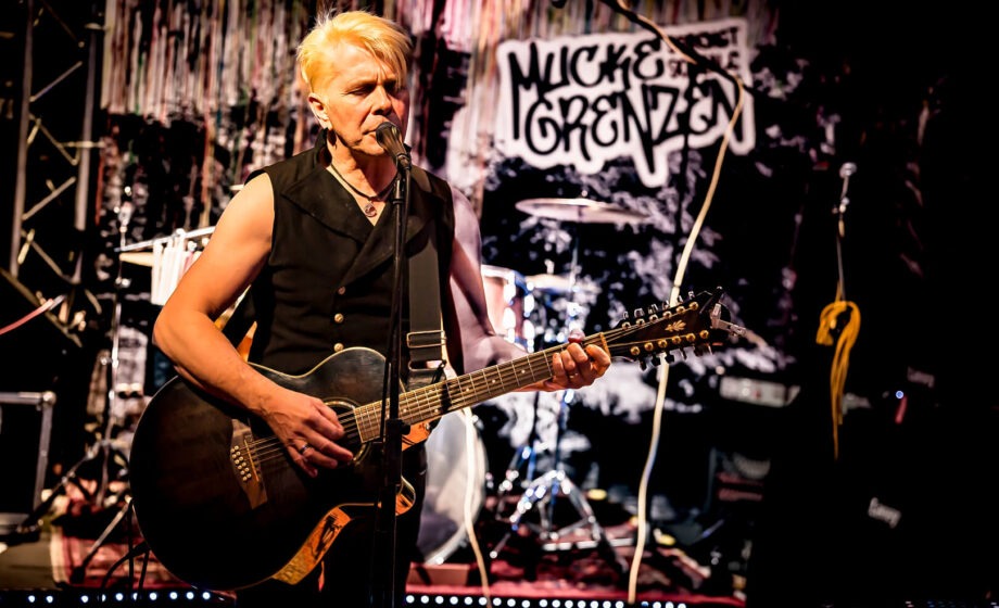 Musiker spielt Gitarre auf Bühne.