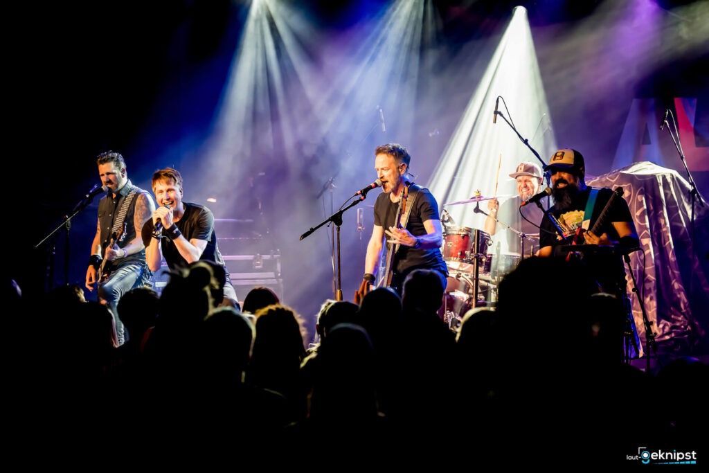 Band spielt Live-Konzert auf Bühne mit Publikum.