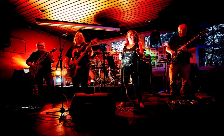 Rockband spielt auf Bühne in rotem Licht.