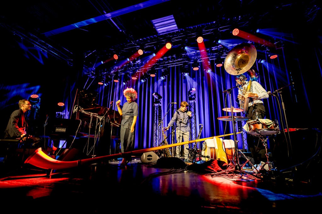 Band spielt live auf Bühne mit Lichtern.