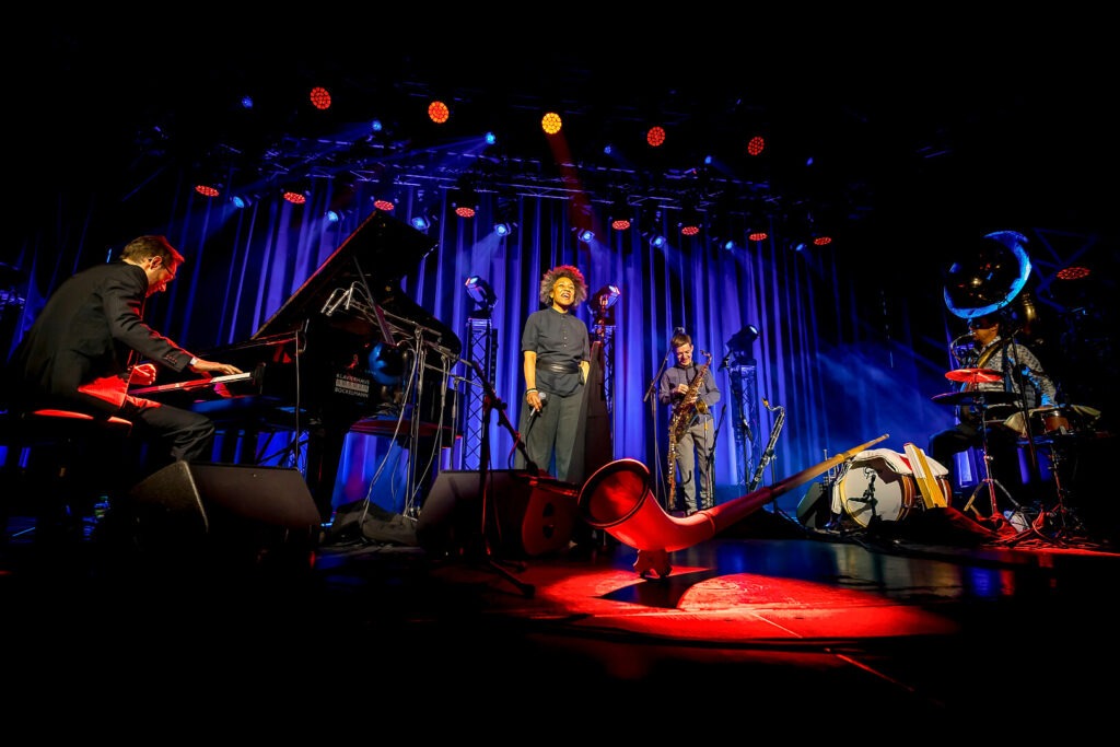 Jazzquartett mit Pianist, Sänger, Saxophonist und Schlagzeuger auf Bühne.