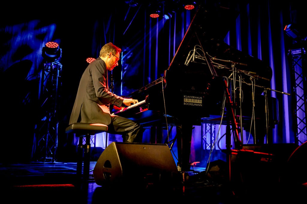 Pianist spielt auf einer Bühne.