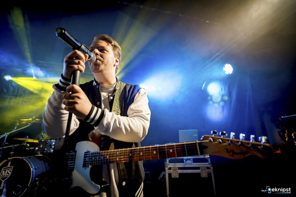 Musiker singt auf der Bühne mit Gitarre