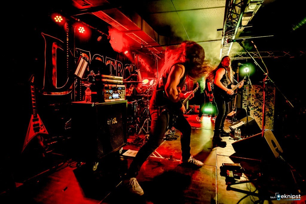 Metalband spielt auf der Bühne mit roter Beleuchtung.