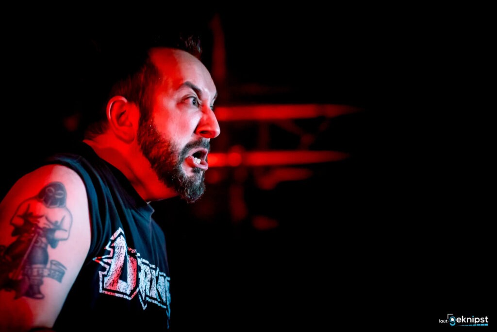 Mann auf Bühne mit Tattoo im roten Licht