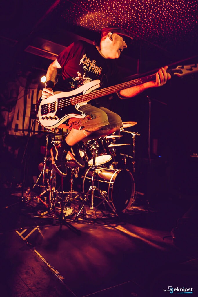 Bassist springt auf einer Bühne während Auftritt