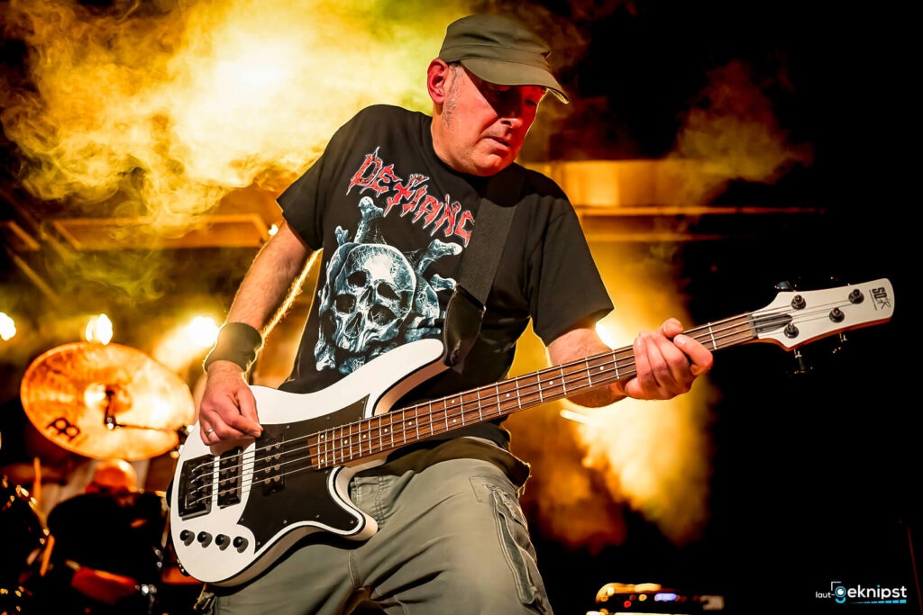 Bassist spielt auf der Bühne unter Lichteffekten.