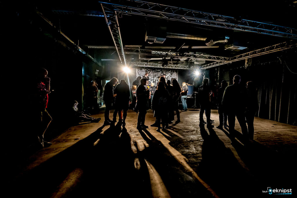 Gruppe Menschen in einem dunklen Club mit Lichtern.