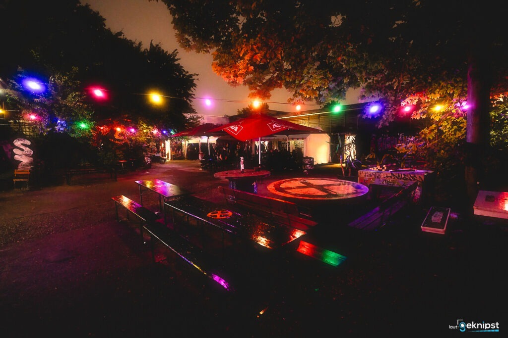 Bunte Lichter beleuchten eine Outdoor-Partyszene im Dunkeln.