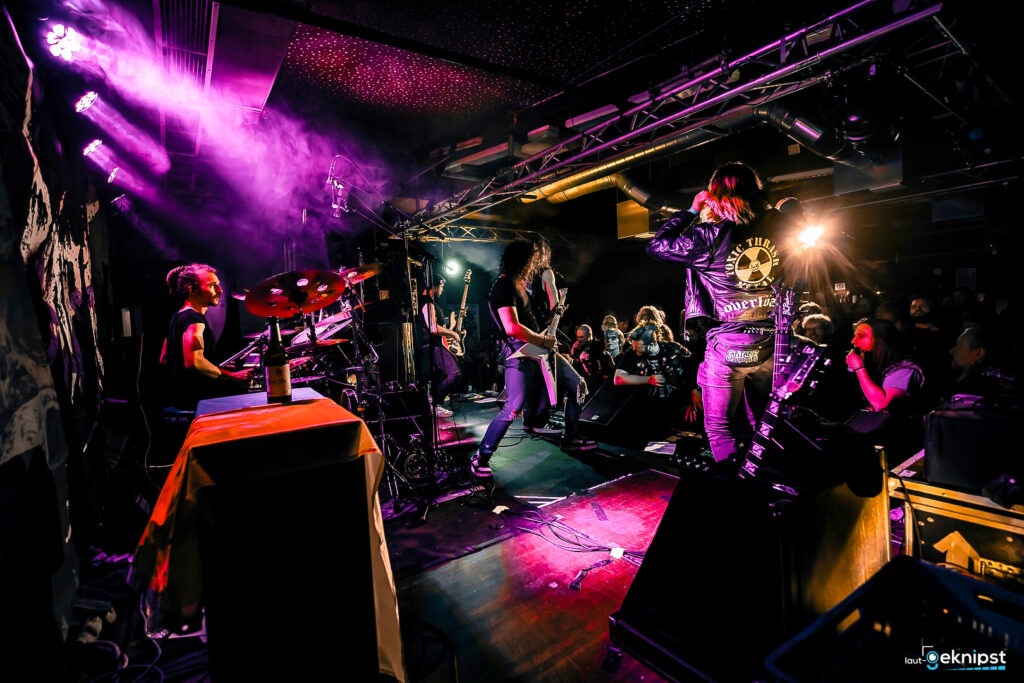 Live-Band spielt auf Rockkonzert mit Publikum im Hintergrund.