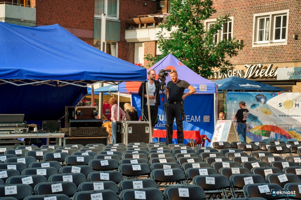 Techniker bei der Eventvorbereitung mit leeren Sitzreihen.