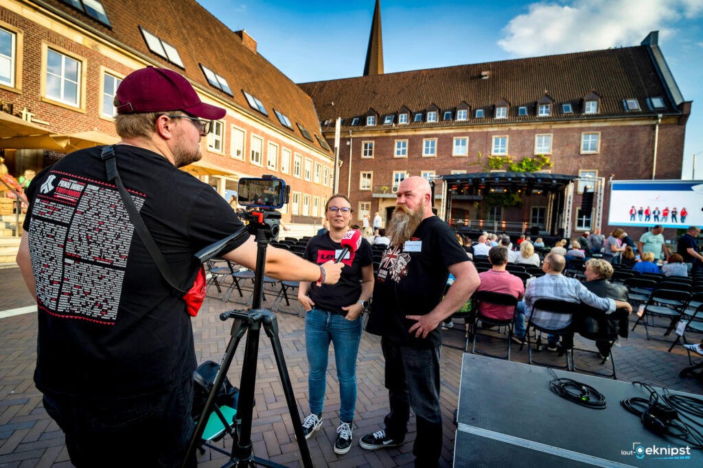 Interviewsituation auf einem Platz mit Publikum.