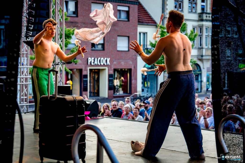 Zwei Künstler jonglieren Hemden vor Publikum.