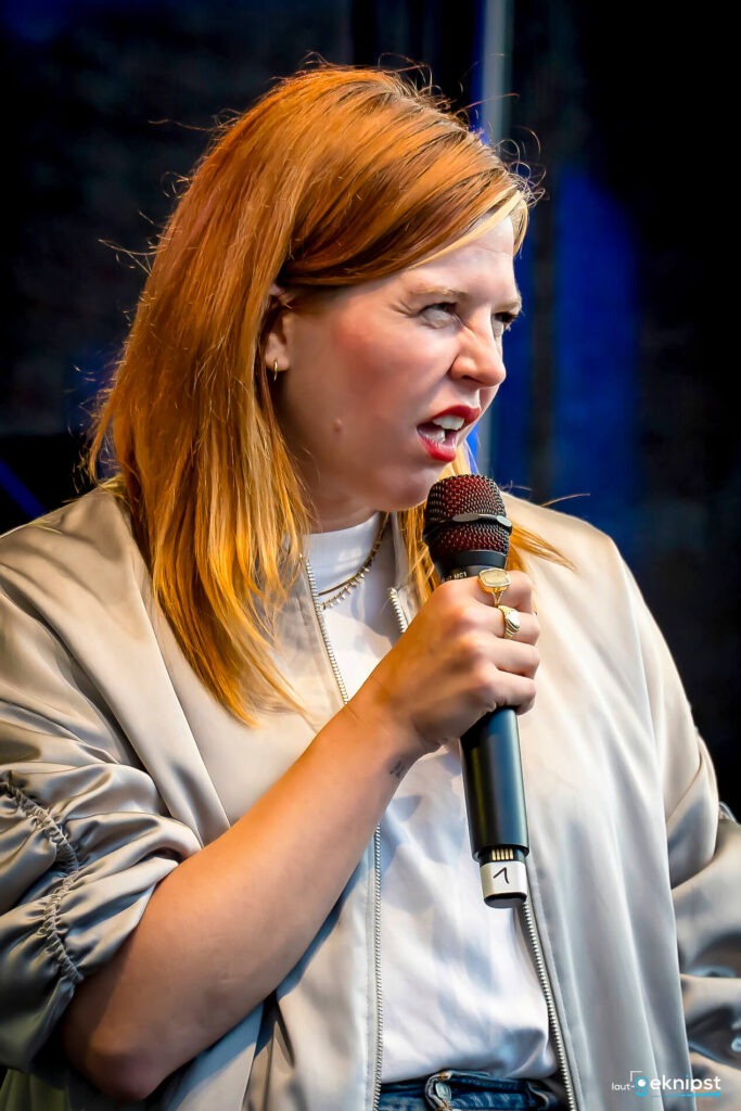 Frau spricht auf Bühne mit Mikrofon