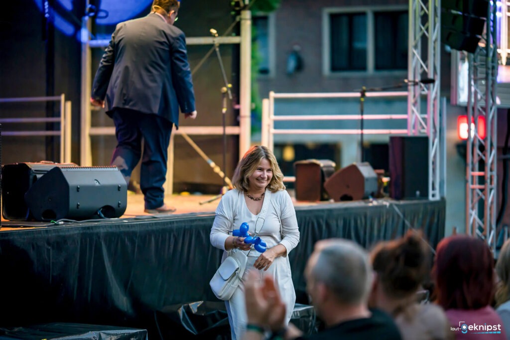Frau mit Ballon auf einer Bühne bei Veranstaltung.