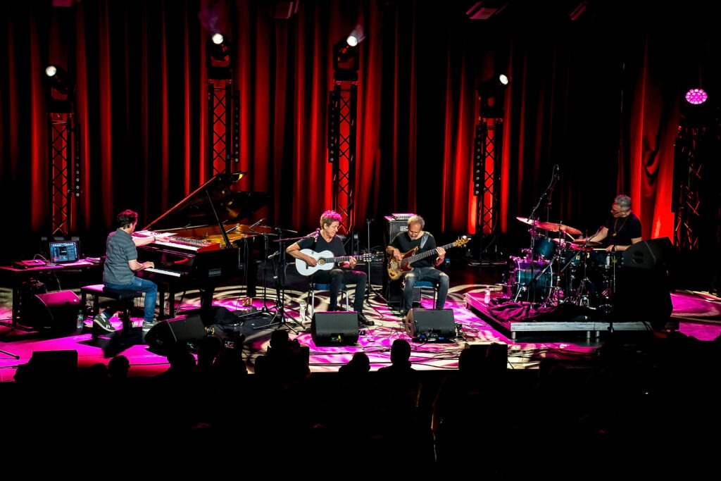 Musiker spielen auf einer Bühne mit rotem Licht.