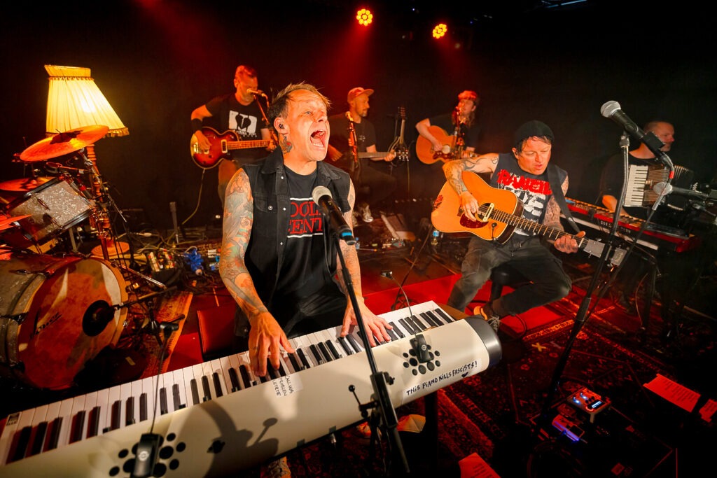 Band spielt Live-Konzert mit Instrumenten auf Bühne.