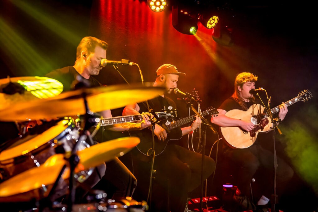 Band spielt live auf der Bühne mit Gitarrenmusik.