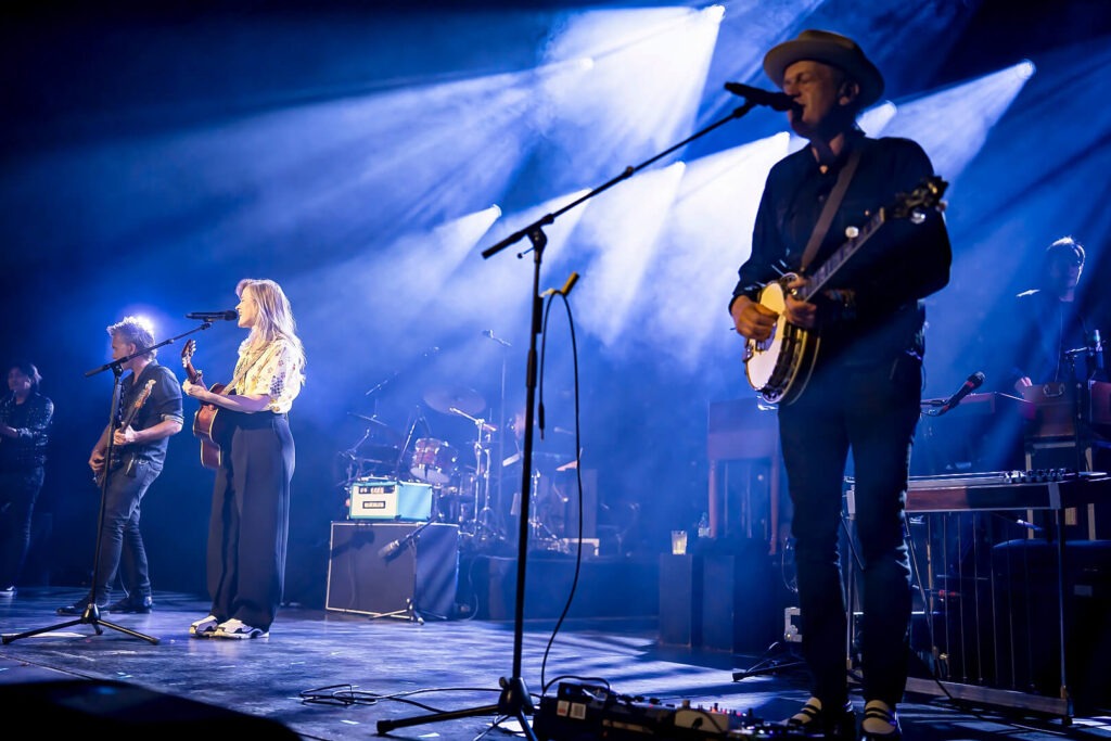 Band spielt Live-Konzert auf Bühne mit Lichteffekten.
