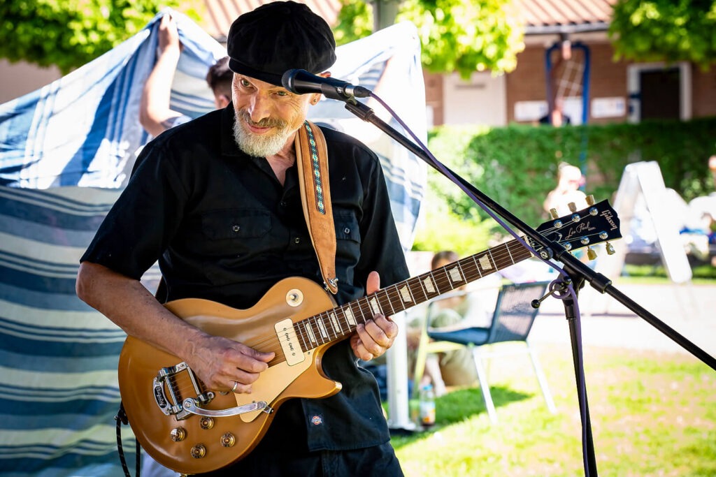 Mann spielt E-Gitarre auf Outdoor-Bühne.