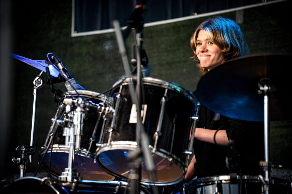 Drummer spielt auf offener Bühne leidenschaftlich Schlagzeug.