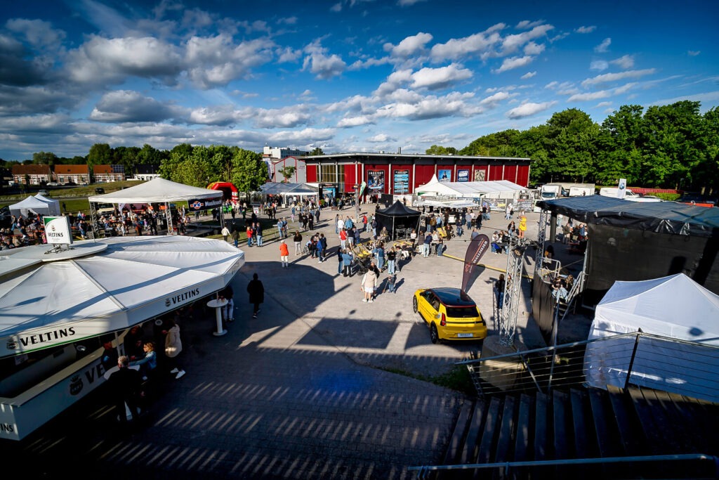 Open-Air-Event mit Ständen und Menschen bei Sonnenschein.