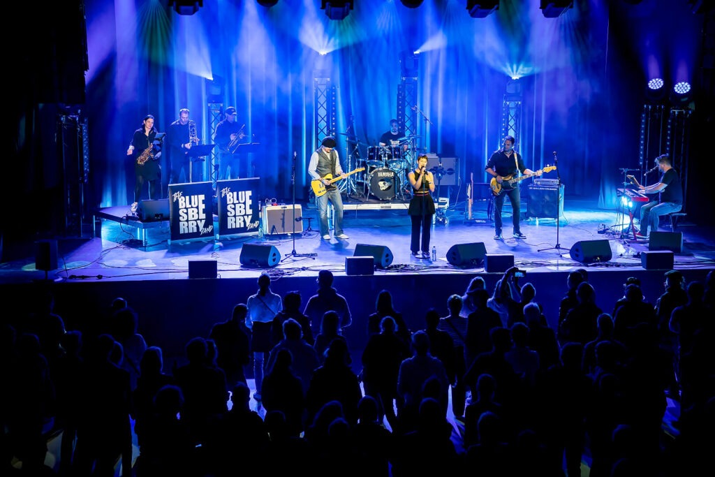 Live-Bandauftritt mit Publikum und farbiger Beleuchtung.