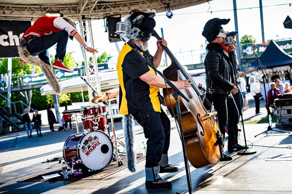 Band spielt live auf Open-Air-Bühne mit Tierkostümen.