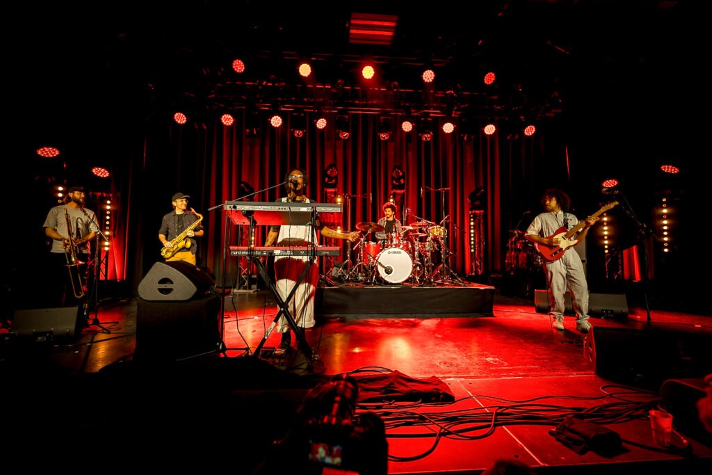 Band spielt auf beleuchteter Bühne mit Instrumenten