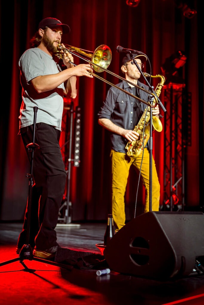 Zwei Musiker spielen Posaune und Saxophon auf der Bühne.